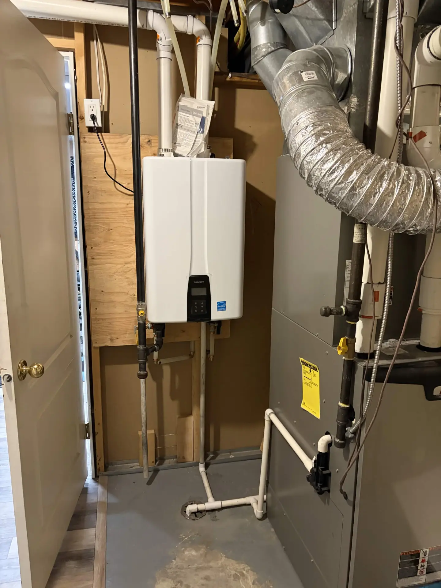 Tankless water heater installed beside a residential furnace