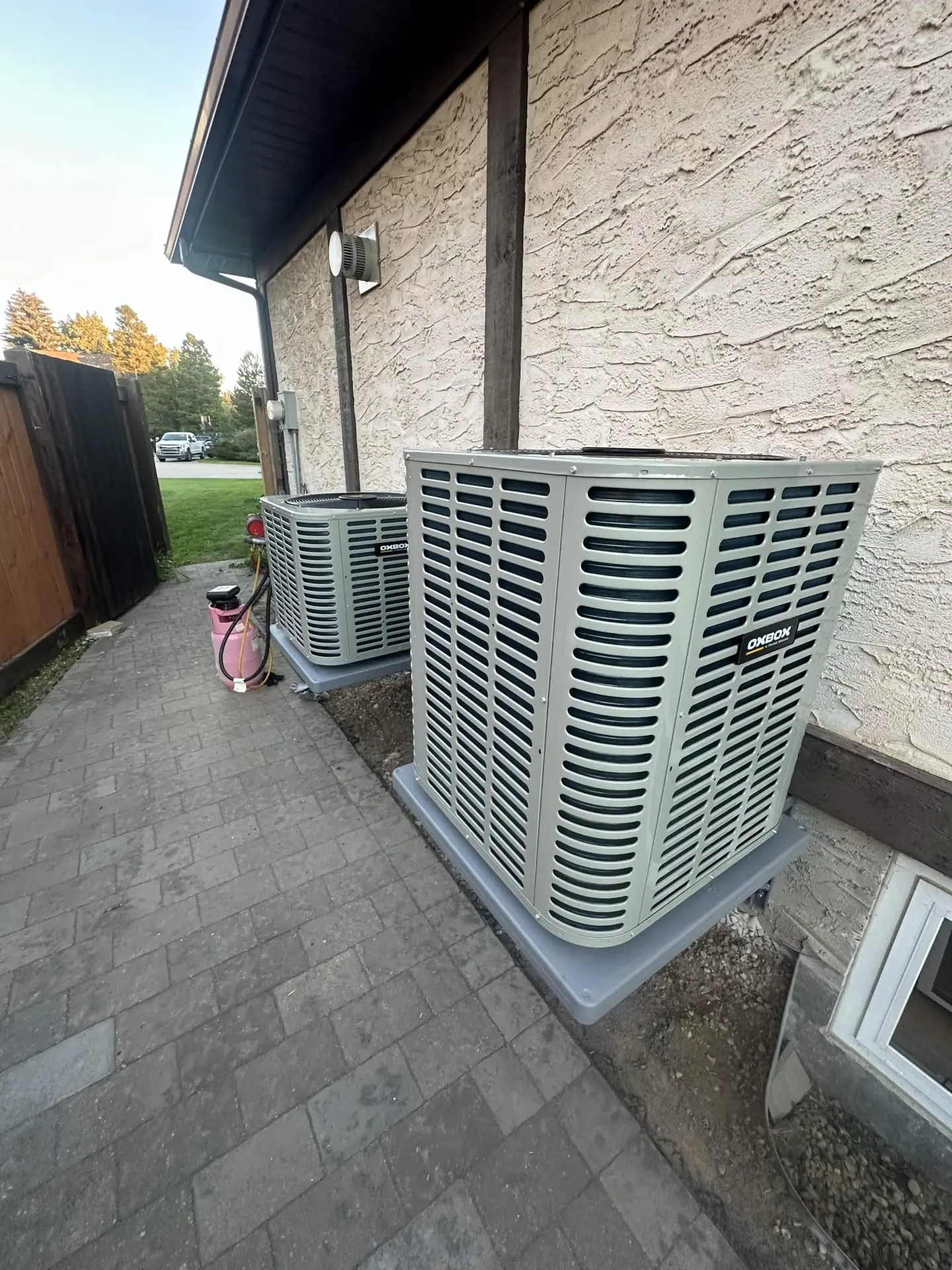 Two OXBOX outdoor air conditioner condensers installed on a stone patio