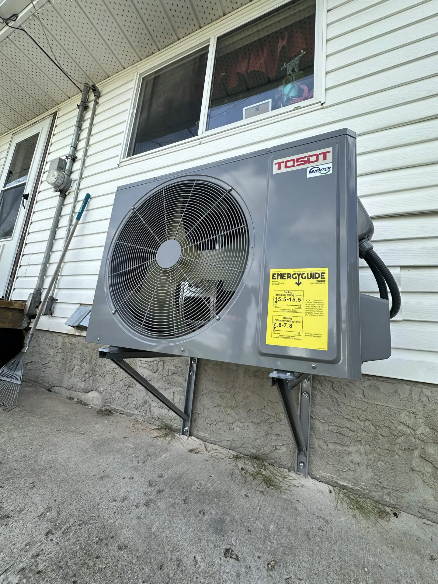 TOSOT inverter heat pump wall-mounted on brackets beside a home
